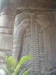Lovely carving on a building serves as an elegant headboard for the people sleeping on the sidewalk beneath it.